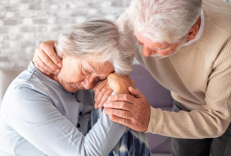 Senior man comforting his elderly wife with hearing loss and dementia symptoms